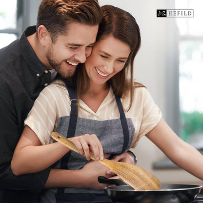 A man holding his wife from behind, who is frying with a natural wooden and polished spatula.