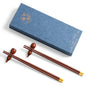 Two pairs of round wooden chopsticks with gold tops, two pairs of gourd chopstick holders and a gift box of chopsticks.